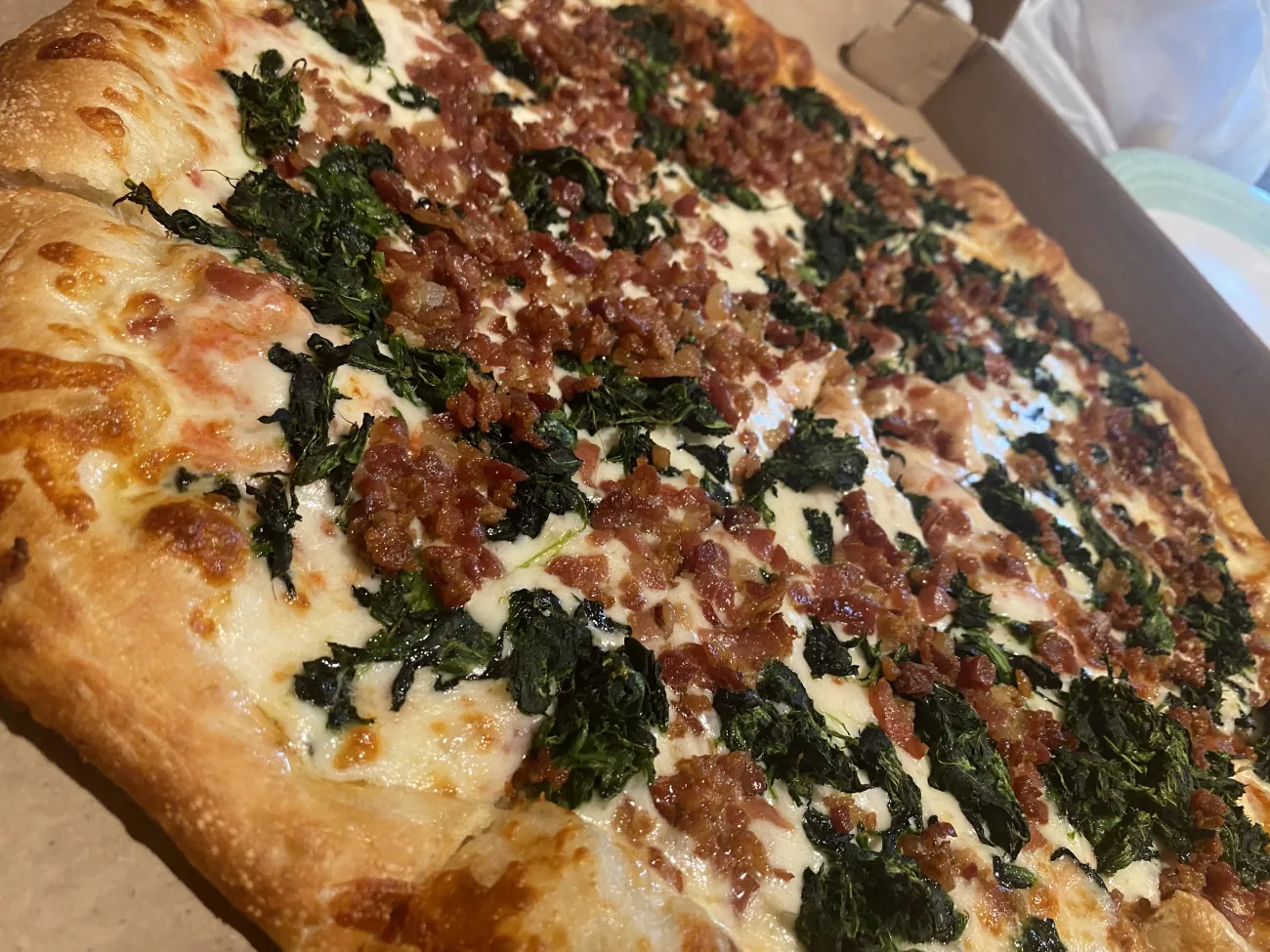 White pizza topped with spinach and crispy bacon